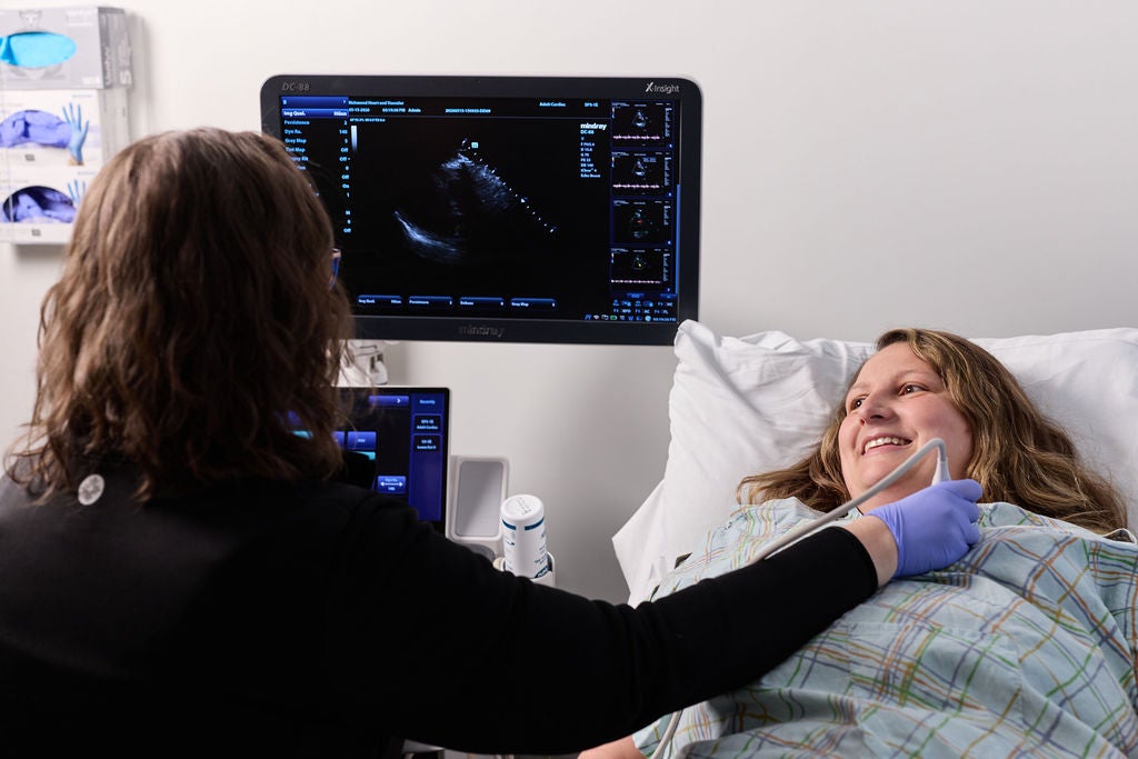 Sonographer performing a diagnostic ultrasound scan on a smiling patient's neck in a clinic setting for Patient Resources