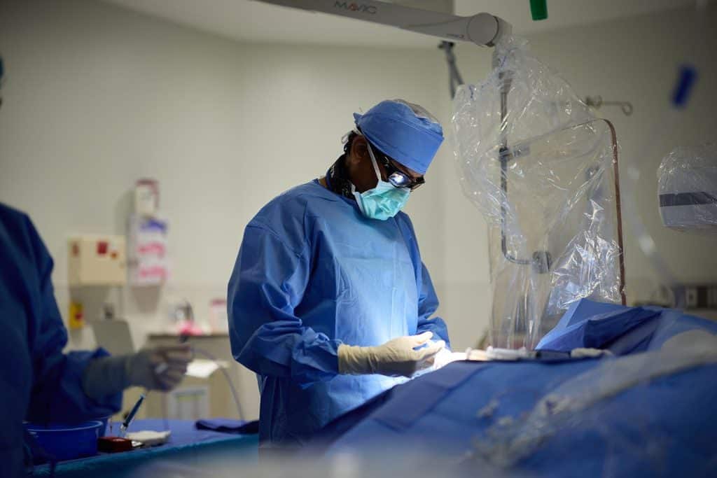 Interventional cardiologist performing a minimally invasive catheterization procedure in a surgical suite for Coronary Artery Disease