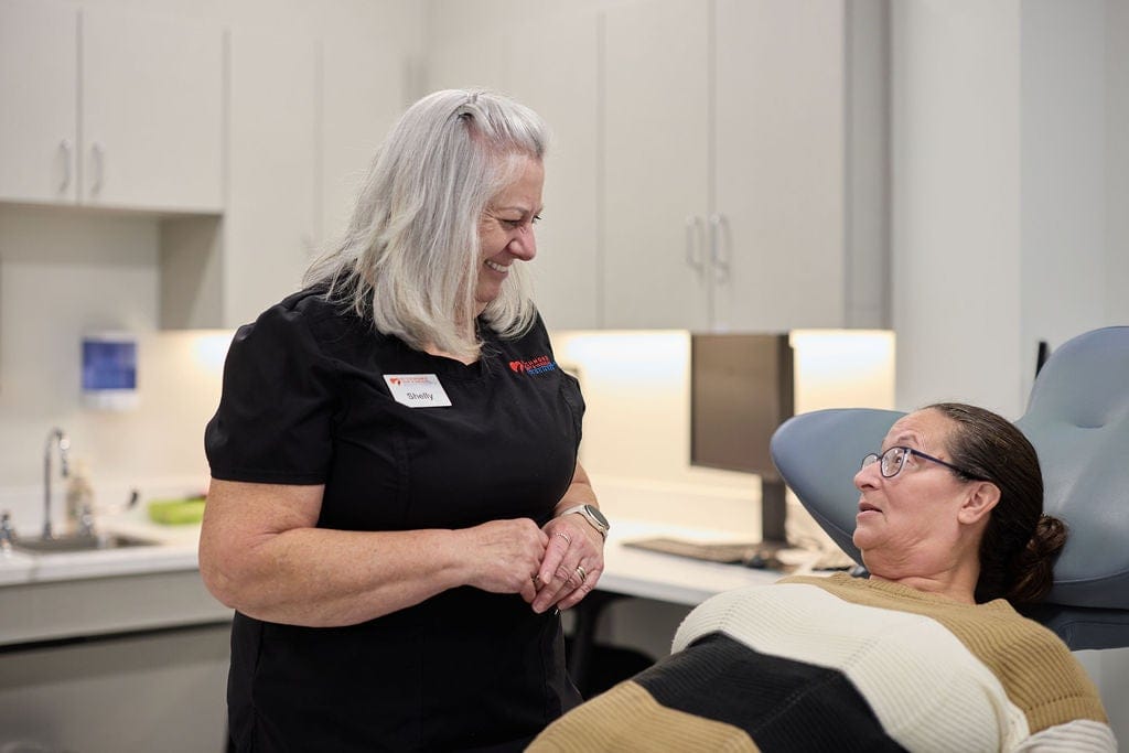 Cardiac nurse speaking with a female patient resting in an examination chair during a consultation for Cardiac Testing