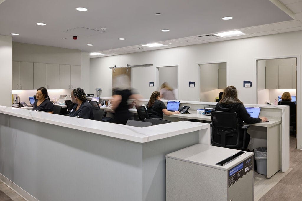 Administrative staff members working at computers behind a modern reception counter in an outpatient clinic for Richmond heart and Vascular service