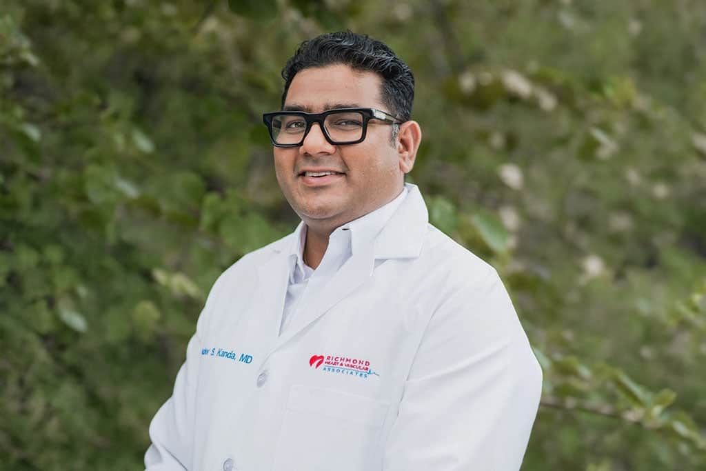 Interventional cardiologist smiling in a white lab coat outdoors for a professional provider portrait of Brinder Kanda