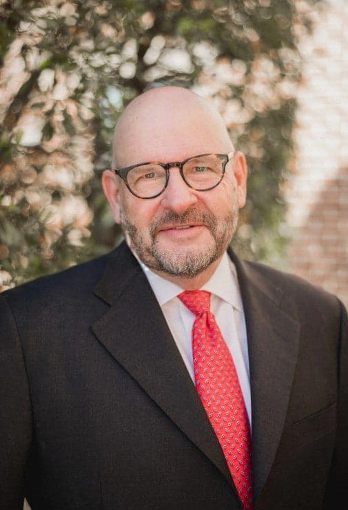 Interventional cardiologist smiling in a dark suit and red tie outdoors for a professional provider portrait of Brian L. Kaminsky