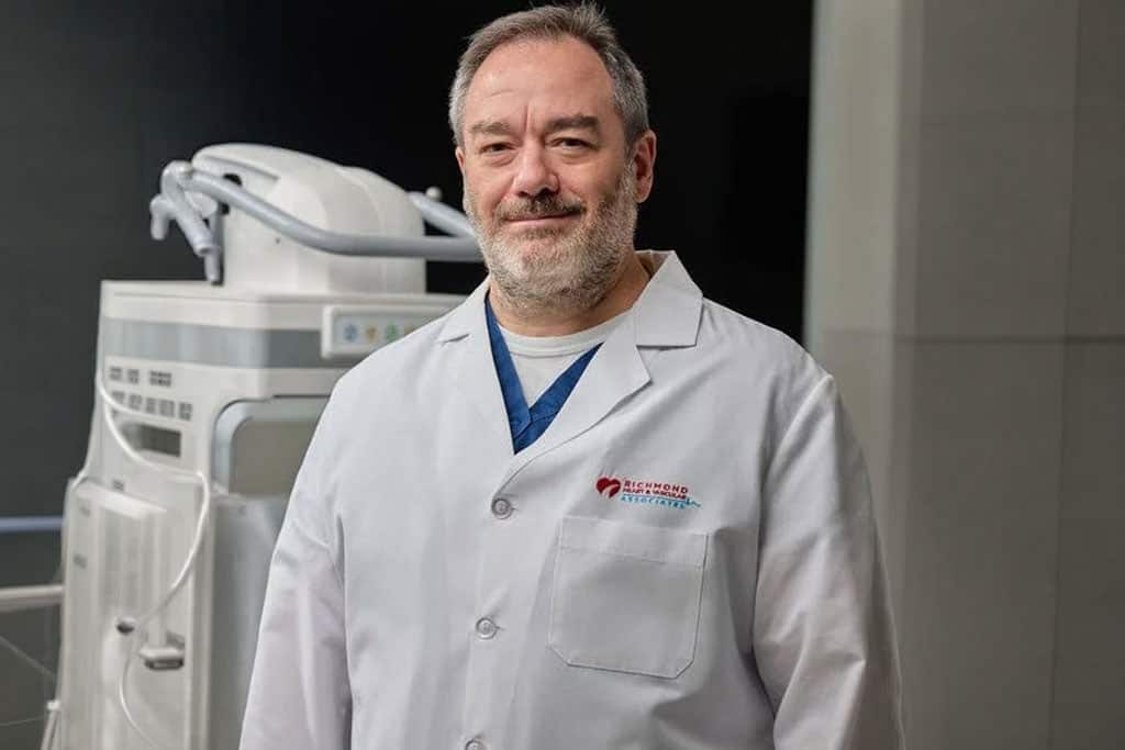 Interventional cardiologist posing in a white lab coat beside cardiac imaging equipment for Ronald Morford, MD