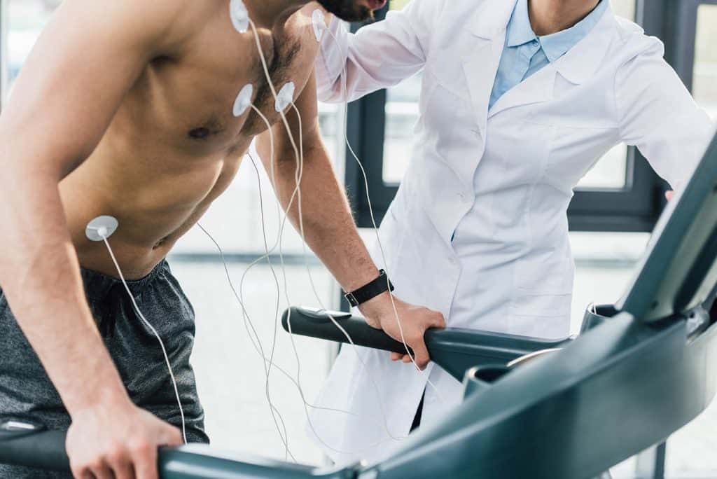Cardiologist supervising a male patient undergoing an exercise stress test on a treadmill for Cardiac Testing
