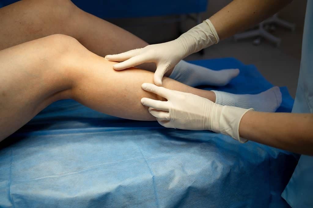 Healthcare specialist examining and palpating a patient's calf during a clinical assessment for vascular care